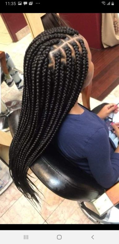 Woman with long, straight braids styled neatly down her back while seated in a salon.