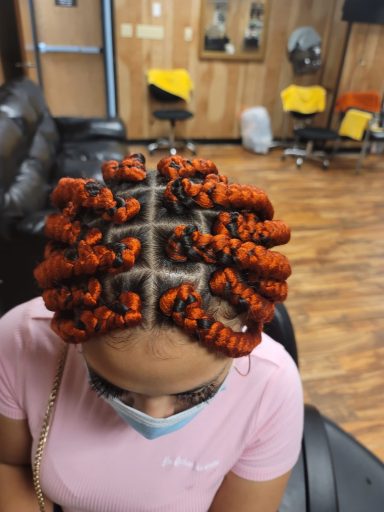 Top view of a person with vibrant orange and black braided hair styled in large twists.